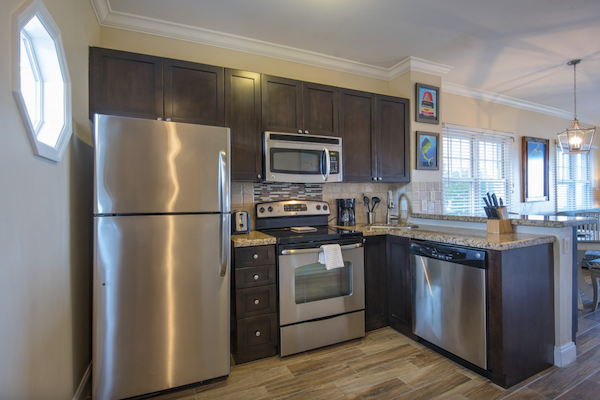 A modern kitchen with stainless steel appliances, dark wood cabinets, and a dining area with a chandelier.