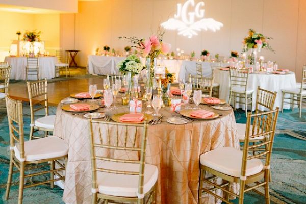 An elegant banquet hall with round tables, chairs, floral centerpieces, and soft lighting, ideal for a wedding or special event setting.