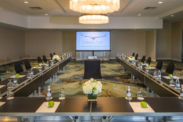 A conference room set up in a U-shape with a screen displaying 