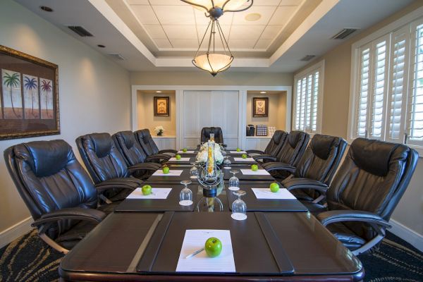 A conference room with a long table, leather chairs, notepads, green apples, and a modern light fixture in the ceiling ends the sentence.