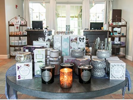 A display table showcasing various scented candles, decorative jars, and skincare products in a store. Perfectly arranged for a cozy ambiance.