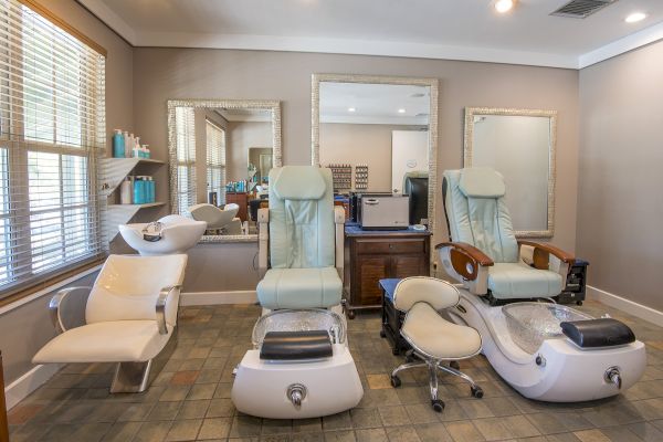 This image shows a well-lit salon with pedicure chairs, a shampoo station, mirrors, and a wooden cabinet.