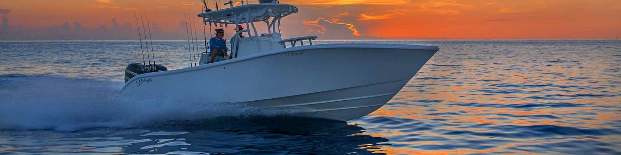 A boat cruises quickly through the water at sunset, with a vibrant sky and calm sea, creating a picturesque and serene scene.