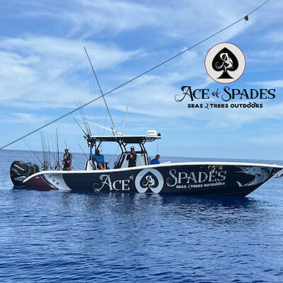 This image shows a fishing boat on the water labeled "Ace of Spades," with people aboard. The sky is clear with some clouds.